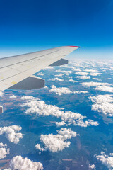 Obraz premium View from the airplane window at a beautiful cloudy sky and the airplane wing
