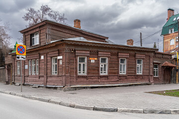 Wooden residential house from 1892 with carved details and white windows under an overcast sky....