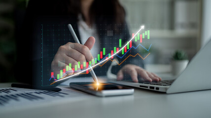 A business professional engages with financial data on a smartphone and laptop, using digital...