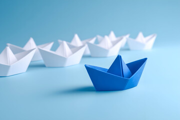 Blue paper boat leads a fleet of white paper boats on a smooth, light blue surface, symbolizing leadership and strategy.