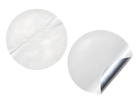 Two round white stickers, one peeled back to reveal a silver backing, isolated on transparent background