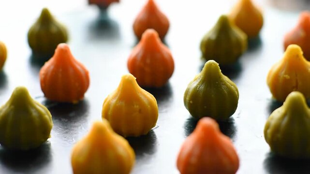 Colorful modak sweets, yellow, orange, green Indian dessert on tray, food background