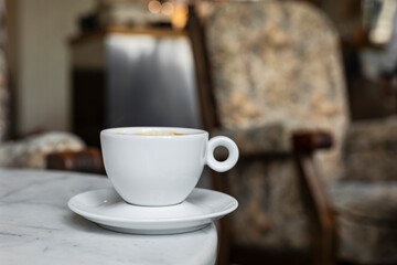 A white cup of black coffee americano in a cozy atmosphere of a cafe with copy space
