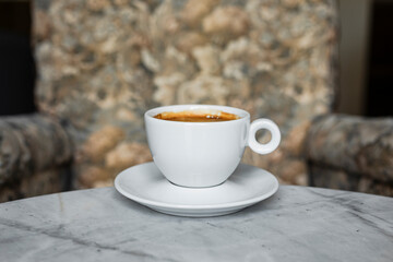 A white cup of black coffee americano in a cozy atmosphere of a cafe with copy space
