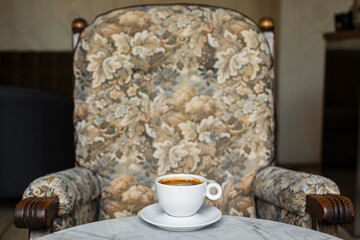 A white cup of black coffee americano in a cozy atmosphere of a cafe with copy space
