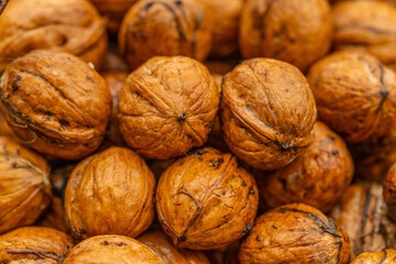 walnuts and kernels captured in a rustic natural setting. Some nuts are cracked open, revealing the rich interior texture, while others remain whole on a dark wooden surface. 