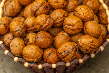 walnuts and kernels captured in a rustic natural setting. Some nuts are cracked open, revealing the rich interior texture, while others remain whole on a dark wooden surface. 