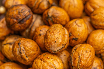 walnuts and kernels captured in a rustic natural setting. Some nuts are cracked open, revealing the rich interior texture, while others remain whole on a dark wooden surface. 
