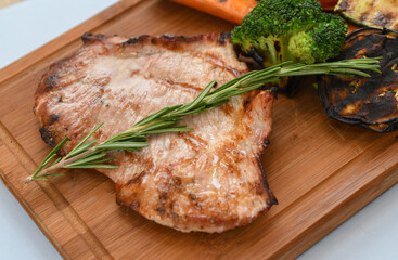 Grilled pork steak with vegetables on a wooden board