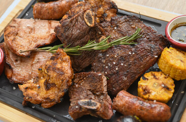 Grilled meat with vegetables and sauce on a wooden board, close-up