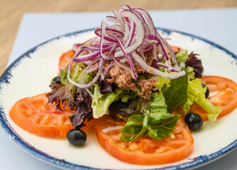 Salad with tuna, lettuce, red onion, black olives and tomato