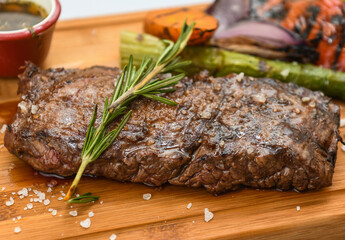 Beef steak with rosemary and vegetables on a wooden board.