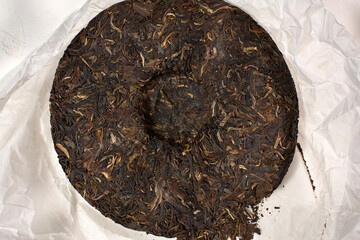 Compressed cake of puer tea showcases its dark leaves and texture.