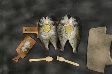 Fresh dorado fish are displayed on a wooden cutting board, garnished with lime slices.