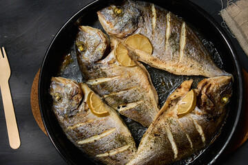 Freshly grilled dorado fish served on a platter with lemon slices and salt for a delicious seafood meal