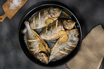 A platter showcasing dorado fish garnished with lemon slices, accompanied by a wooden board