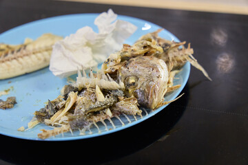 Dorado fish served on a plate with bones and remnants after a meal