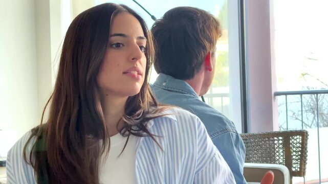 Serious couple sitting on sofa at home talking and confronting each other, thoughtful and sad mood as if during relationship therapy or difficult conversation, concept of communication, crisis and emo