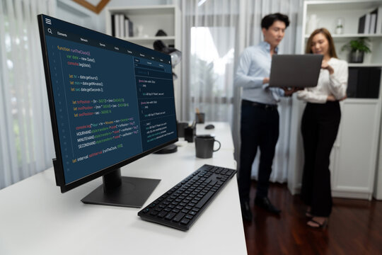 Running on coding programming intelligence system on computer screen with blurry IT developers standing with laptop at corner modern office, talking online software development information. Infobahn.