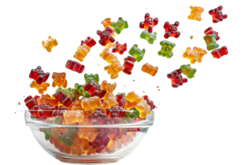 Colorful gummy bears cascade dramatically from a clear bowl against a bright white backdrop