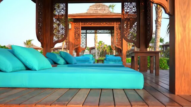 Luxury outdoor daybed with turquoise cushions in tropical resort setting. Relaxation and tranquil vacation concept.