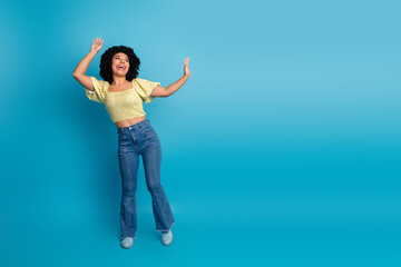 Joyful young woman in stylish outfit celebrating on blue background showcasing positive emotions and cheerful energy