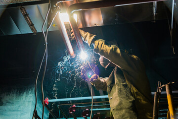 Metal soldering by welding method. A man using a welding machine solders metal in production. 