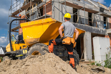 Construction Worker Operating a Dumper Truck at a Building Site on a Sunny Day