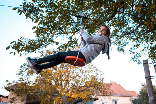 Girl zip lining outdoors in autumn playground - Powered by Adobe