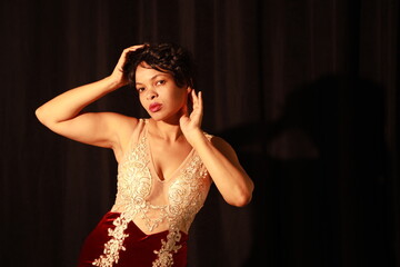 Low key portrait of a beautiful young dark curly haired woman in a red evening dress