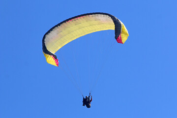 Tandem Paraglider flying in a blue sky