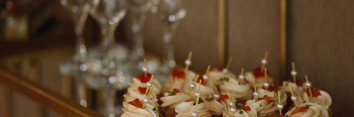 Small canapes with cream and red caviar on a mirrored tray near empty champagne glasses. Warm light, gold accents, soft background. Concepts: catering, luxury event, celebration, gourmet food.