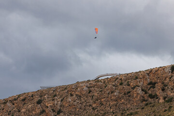 Parapente no reconocible con nubes y pared vertical junto al mirador del faro de Santa Pola, Espa&ntilde;a