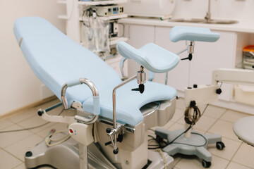 Girl awaits consultation in a gynecological office with specialized tools. Woman seated in gynecology chair before examination. Modern gynecological chair and microscope ready for gynecology exam.