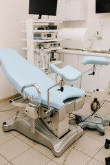 Woman seated in gynecology chair before examination. Modern gynecological chair and microscope ready for gynecology exam. Girl awaits consultation in a gynecological office with specialized tools.