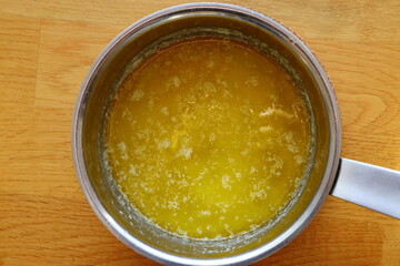 Melting butter in a saucepan. Cooking food. Wooden background.