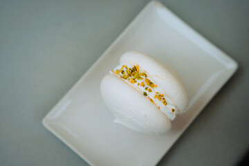 Exquisite macarons: a pristine meringue shell filled with creamy pistachio goodness. Captured in detail on a simple plate. Perfect for food photography, luxury branding, and elegant visuals.