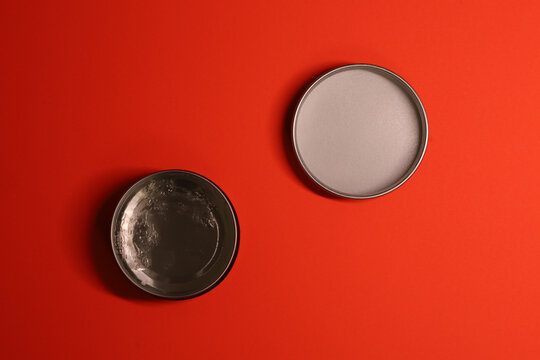 This is a vibrant minimalistic composition of two round plates on a rich red background. One plate is clean and light grey, while the other, darker one, has food residue, creating a contrast between e