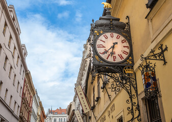 Prague, Czech Republic, August 7, 2023. A shot of the entrance to the U Fleku brewery, the oldest and most famous in the city. The beautiful vintage street clock is prominent. Travel destinations.