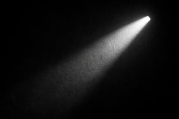 A solitary beam of light cuts through the darkness, illuminating a small area. The stark contrast between light and shadow creates a dramatic mood.AI generated.