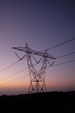 Power lines silhouette during dusk hours, small plane in the background.