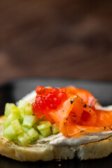 Gourmet canapé with smoked salmon, red caviar, cucumber, and creamy spread on toasted bread. Elegant appetizer for catering, events, or fine dining presentations.