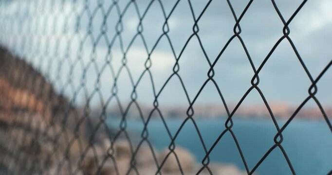 Coastal vista through chain link fence at sunset