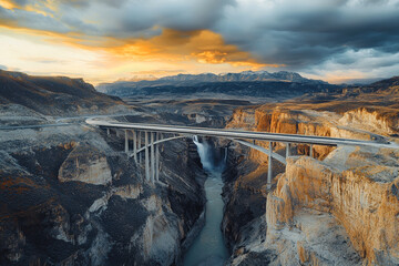 Mountain bridge over canyon at sunset, scenery of dramatic clouds and river gorge in scenic landscape in summer, aerial view.