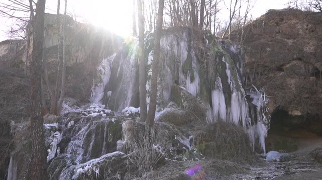 A frozen waterfall on a mountain river. The Bigar waterfall below Stara Planina is bound by ice, you can see ice stalactites and other ice forms, and some unfrozen water falling. The camera is static