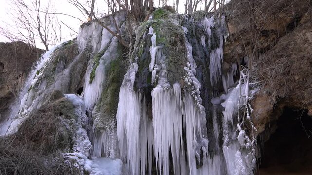  A frozen waterfall on a mountain river. The Bigar waterfall below Stara Planina is bound by ice, you can see ice stalactites and other ice forms, and some unfrozen water falling. The camera is static