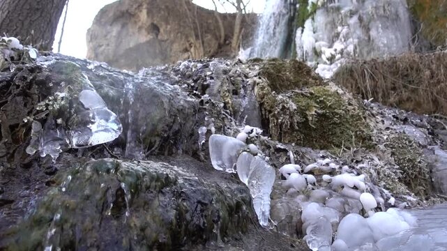  A frozen waterfall on a mountain river. The Bigar waterfall below Stara Planina is bound by ice, you can see ice stalactites and other ice forms, and some unfrozen water falling. The camera slides 