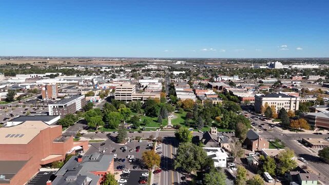 Aerial view of Lincoln Park surrounded by buildings and streets; a vibrant scene with lush green trees and clear blue skies, Greeley, Colorado, United States.