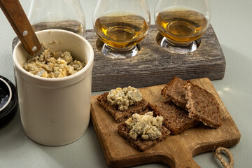 Matured strong british blue cheese stilton keeping in ceramic bowl under wax layer, cheese and whiskey pairing