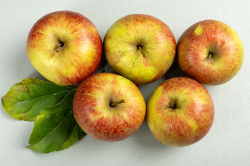 New harvest of french sweet red green apples, tasty healthy fruits with green leaves